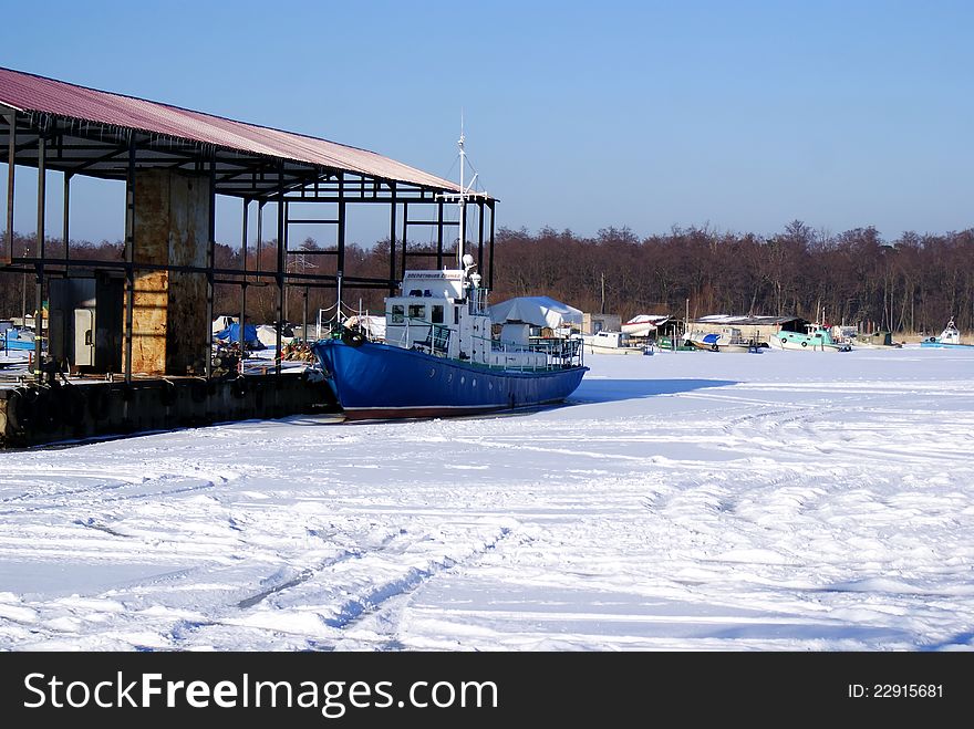 Small boat squeezed next to an ice dock. Winter is a clear frosty weather. Small boat squeezed next to an ice dock. Winter is a clear frosty weather.