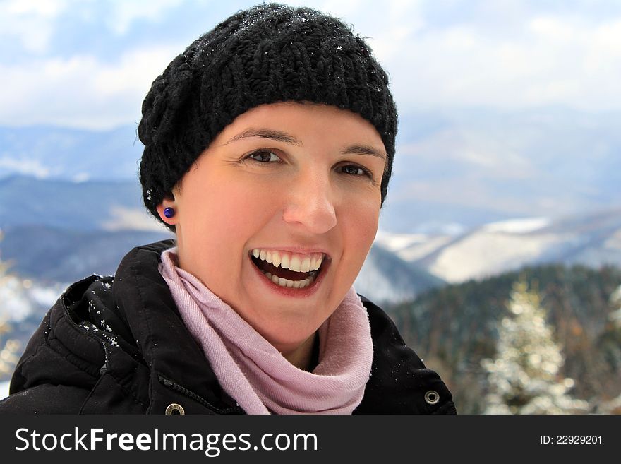 Happy young woman with a big smile on her face, spending her winter holiday in a mountain cabin, happiness concept