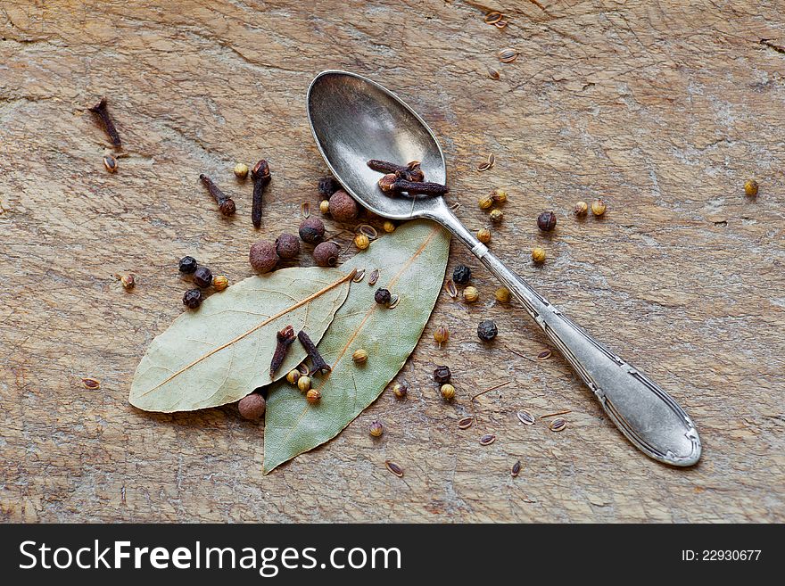 Spices and spoon on a wooden board.