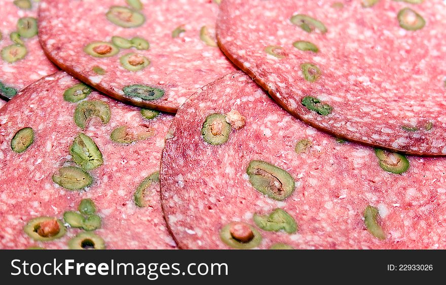 Salame slices with green olives closeup