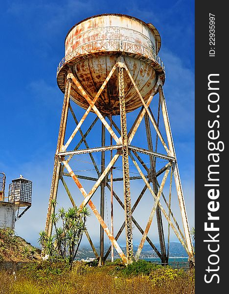 Rusty water tank tower on blue sky background