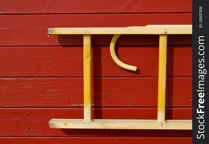 Wooden emergency rescue ladder hanged over a red wall. Wooden emergency rescue ladder hanged over a red wall