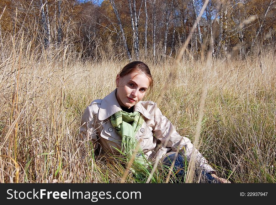 The girl sitting in the grass. Autumn day. The girl sitting in the grass. Autumn day.