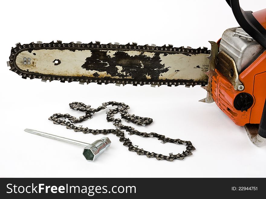 A chain saw with a replacement chain and a tool for installation on a white background into. A chain saw with a replacement chain and a tool for installation on a white background into.