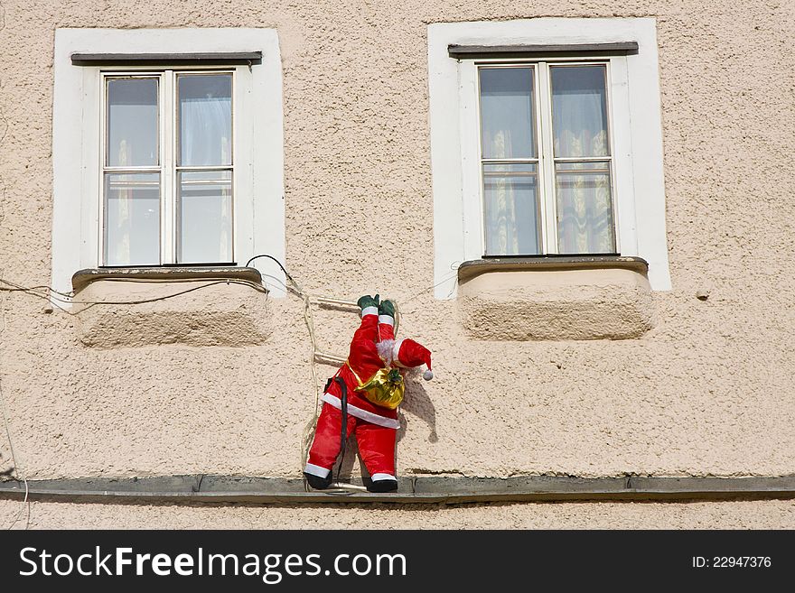 Red-clad Santa doll trying to get into the house window. Red-clad Santa doll trying to get into the house window.