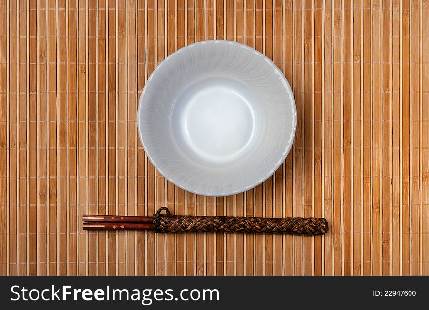 Asian style bowl and chopstick on bamboo background.