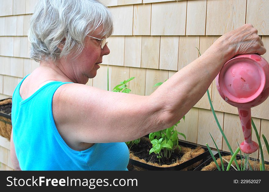 Country woman watering her plants outside.