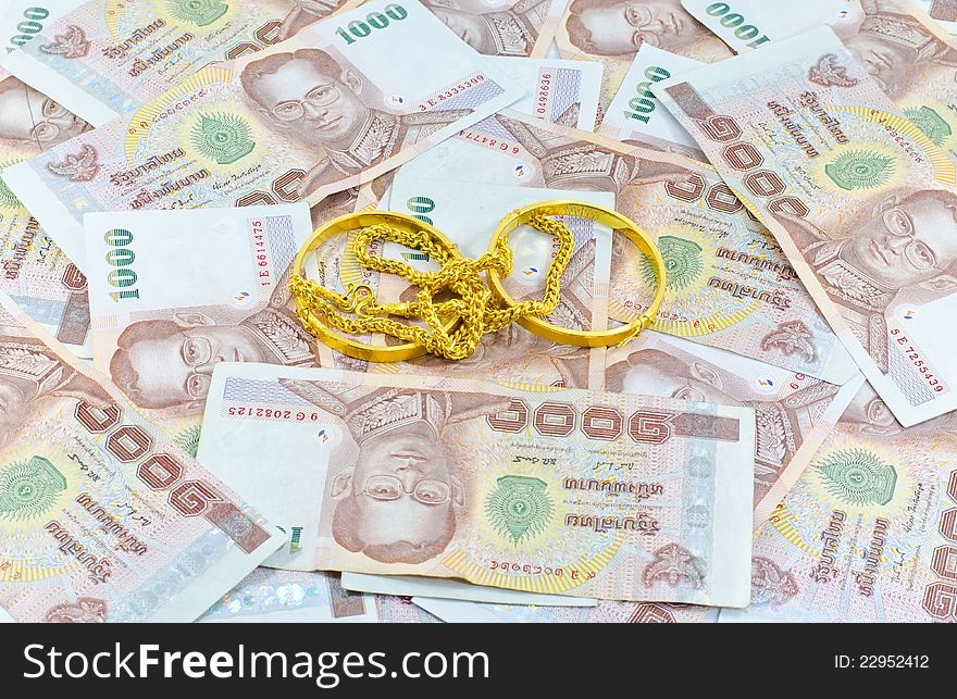Gold chain an gold bracelet placed up to Thai money background. Gold chain an gold bracelet placed up to Thai money background.