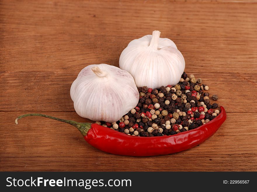 Red hot chilli pepper, ground peppers and two white garlics over wooden background. Red hot chilli pepper, ground peppers and two white garlics over wooden background