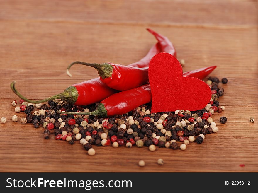 Red hot chili peppers with heart shape over wooden background. Red hot chili peppers with heart shape over wooden background