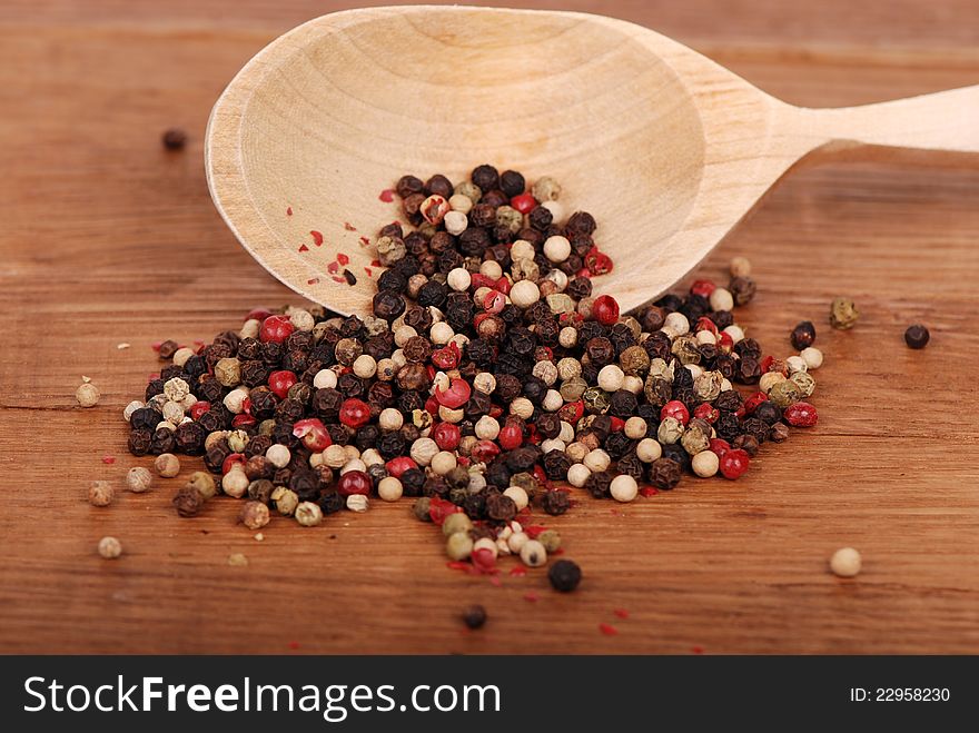 Studio shot of white, red and black ground peppers with new spoon on old wooden background/