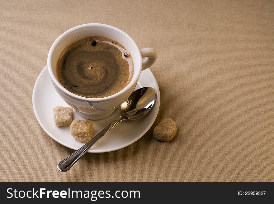 Black coffee cup with brown sugar over textured background