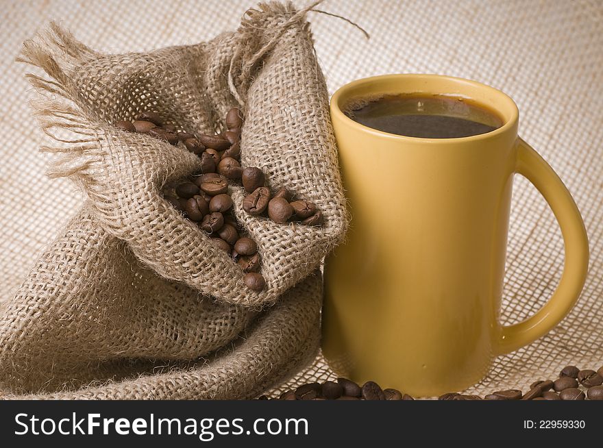 Cup of coffee with beans and sack over brown burlap background. Cup of coffee with beans and sack over brown burlap background