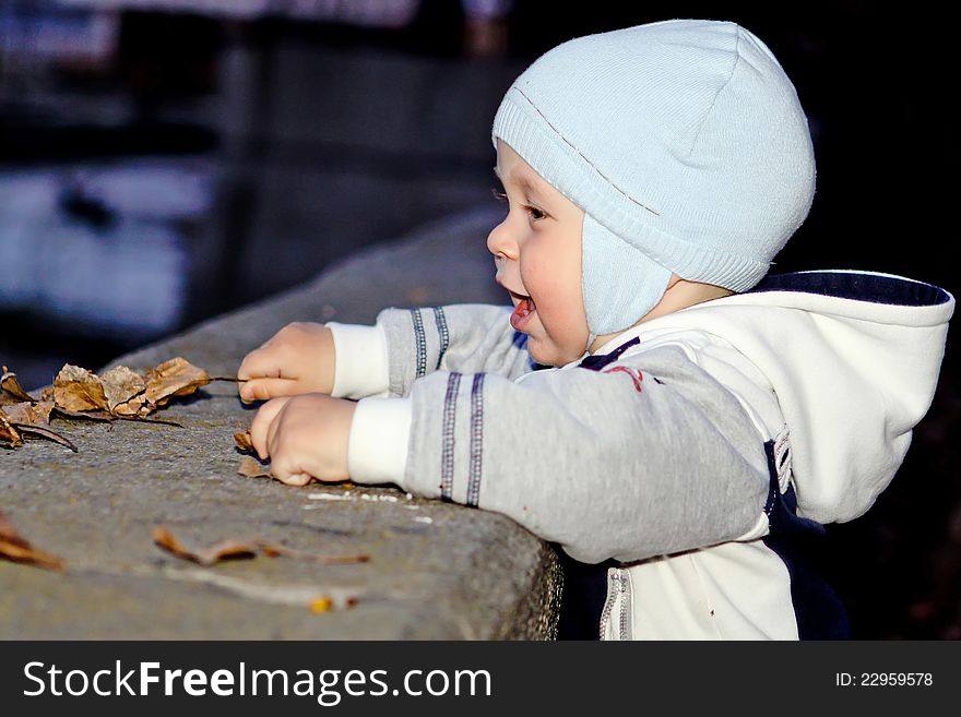 Boy smiles on river bank in the evening and holds a leaf