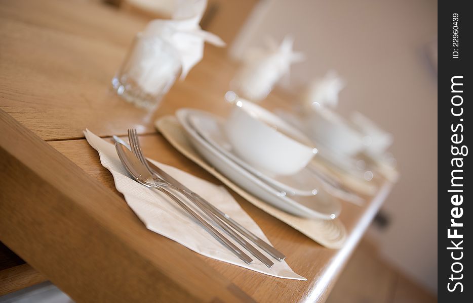 White crockery breakfast place setting on a wooden kitchen table angled shot