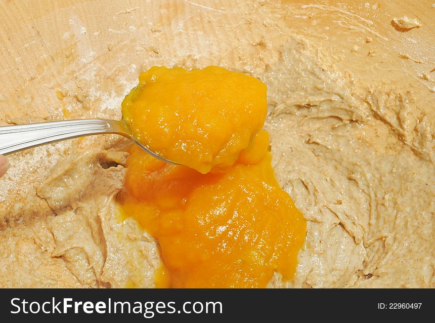 Pumpkin puree being added into a bowl with dough for a pumpkin pie. Pumpkin puree being added into a bowl with dough for a pumpkin pie