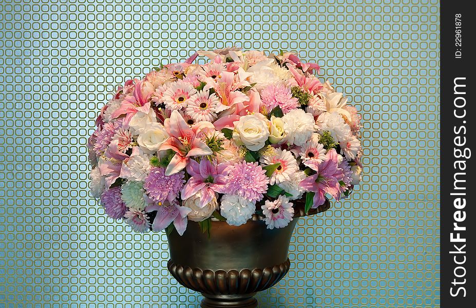 Bouquet of flowers in a brass vase, textured walls in the background