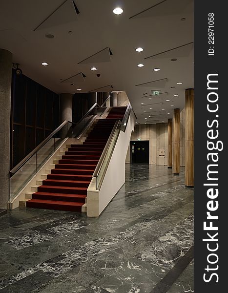 Stairs in theatre with red carpet and grey/green marble floor