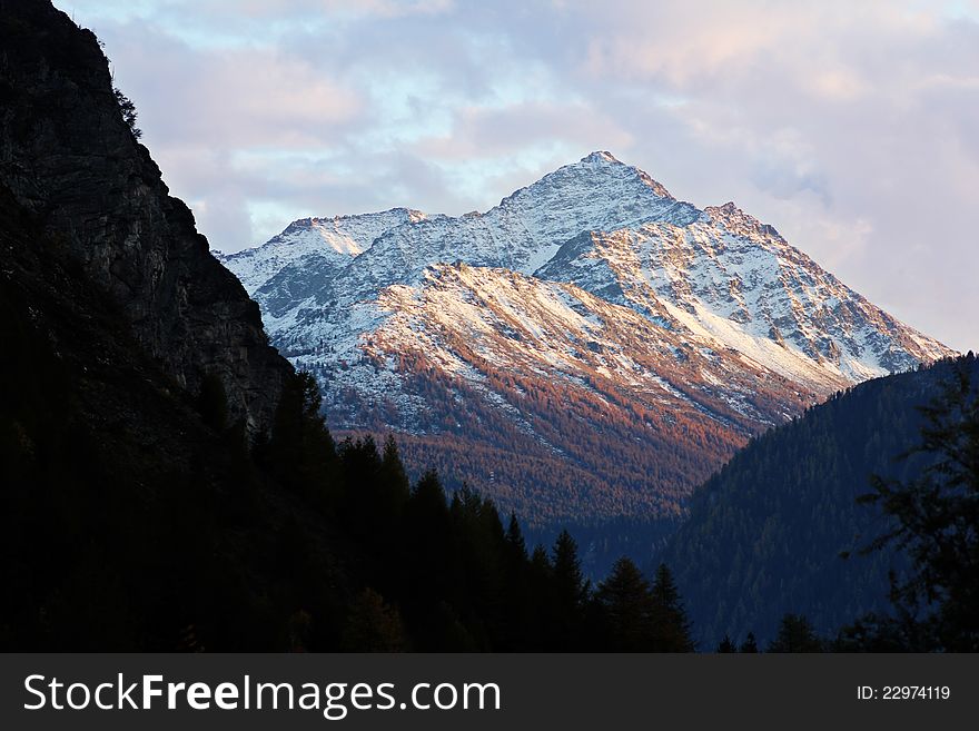 Snowy mountain peak is softly touched by last sunset light. Snowy mountain peak is softly touched by last sunset light