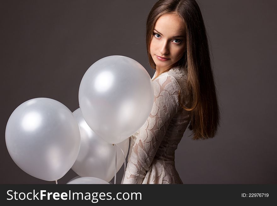 Beautiful fashion woman in studio with white balloons