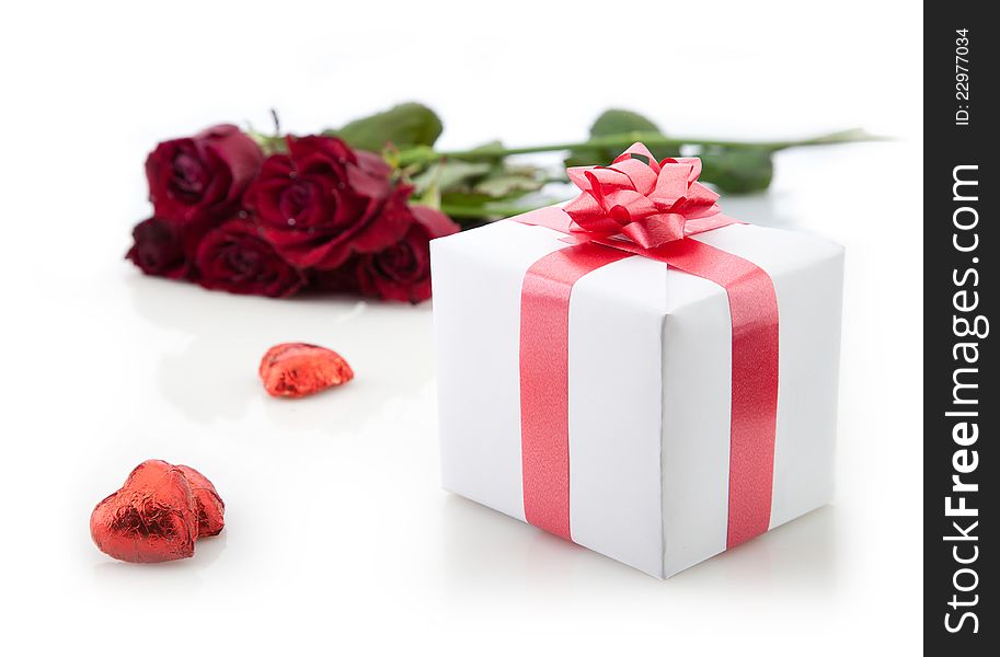 A bouquet of roses and gift box with red ribbon on white background. A bouquet of roses and gift box with red ribbon on white background.