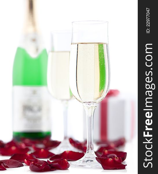 Two glasses of champagne, gift box, rose petals on white background. Two glasses of champagne, gift box, rose petals on white background.