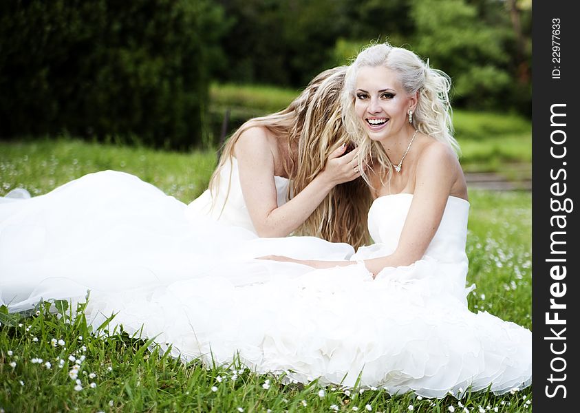 Two beautiful bride in a garden in white dresses. Two beautiful bride in a garden in white dresses