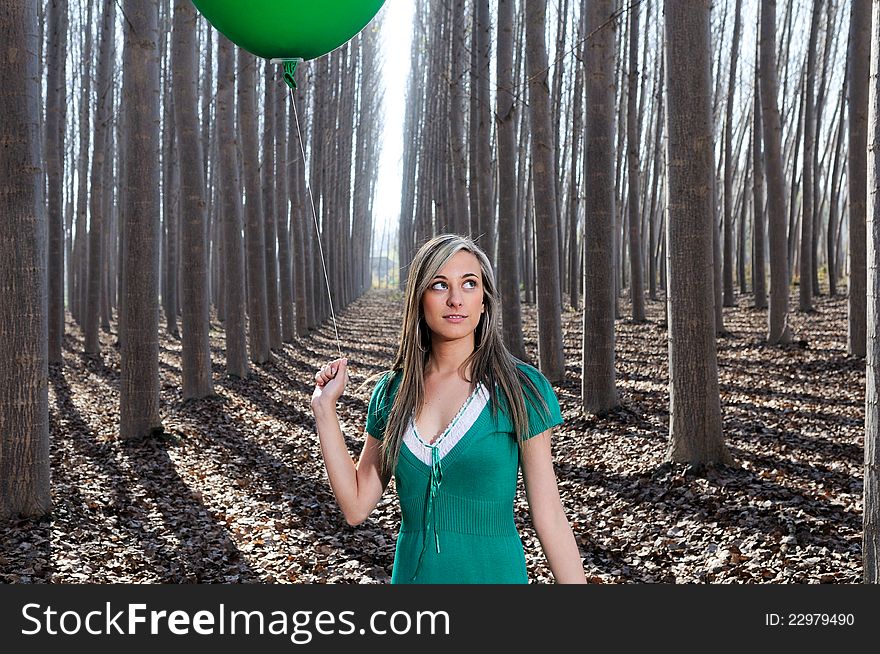 Beautiful blonde girl, dressed in green, standing in the forest. Beautiful blonde girl, dressed in green, standing in the forest