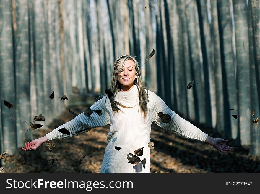 Beautiful blonde girl with falling leaves in the autumn park