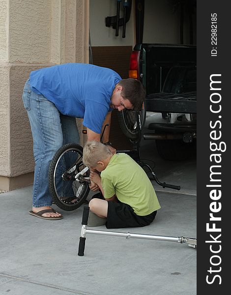 A boy and his dad fix a bike. A boy and his dad fix a bike