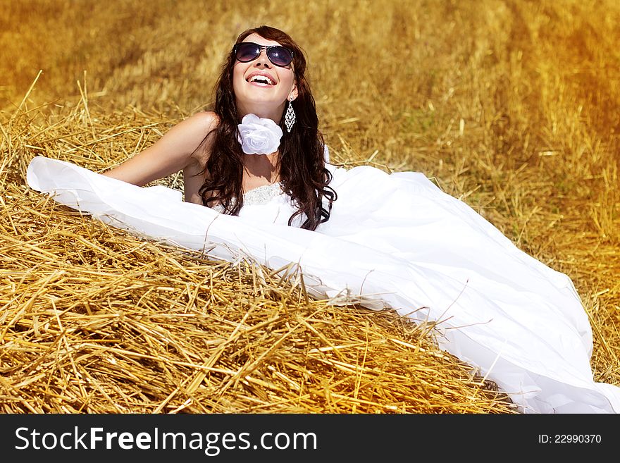 Beautiful bride relaxing in hay stack at her wedding day