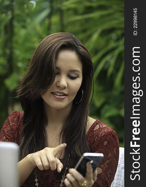 Portrait of a beautiful young woman with her laptop and cell phone outdoors