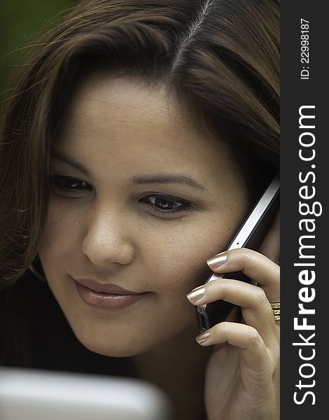 Portrait of a beautiful young woman with her laptop and cell phone outdoors