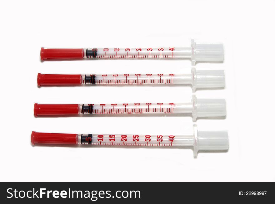 Four insulin syringes with needles on a white background. Four insulin syringes with needles on a white background