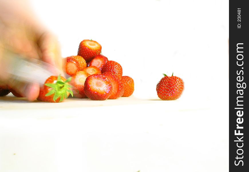 Blurred hand slicing fresh strawberries - isolated. Blurred hand slicing fresh strawberries - isolated