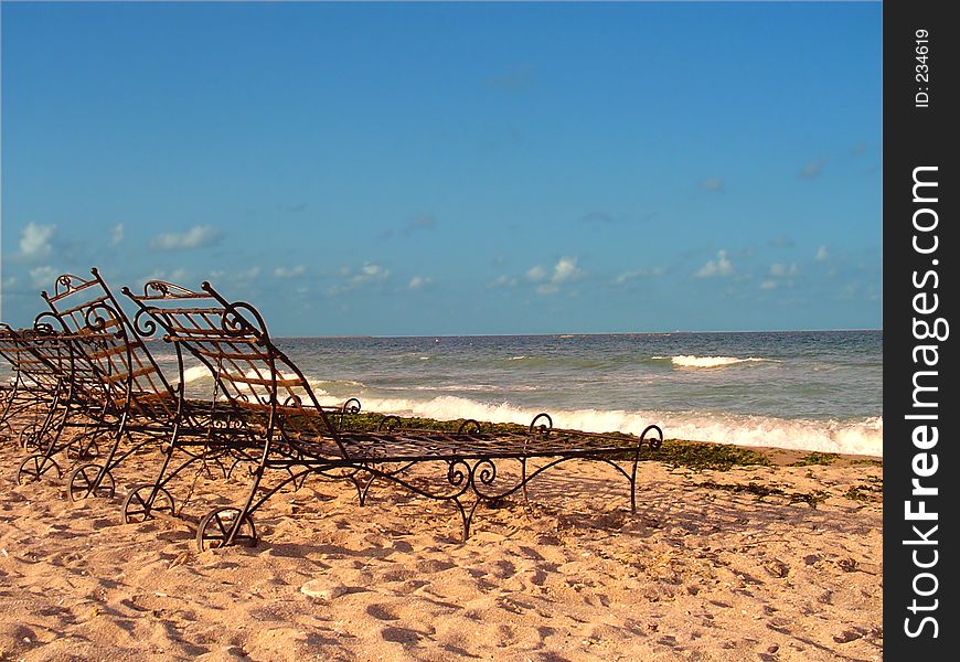 Landscape at the seaside with three metal sunbeds.