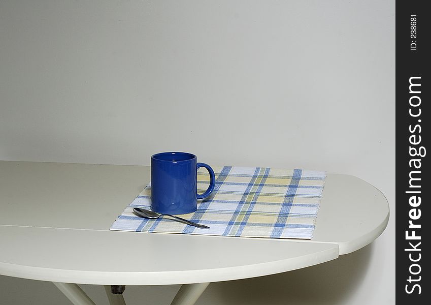 A coffee mug sitting on a blue/yellow/white placemat