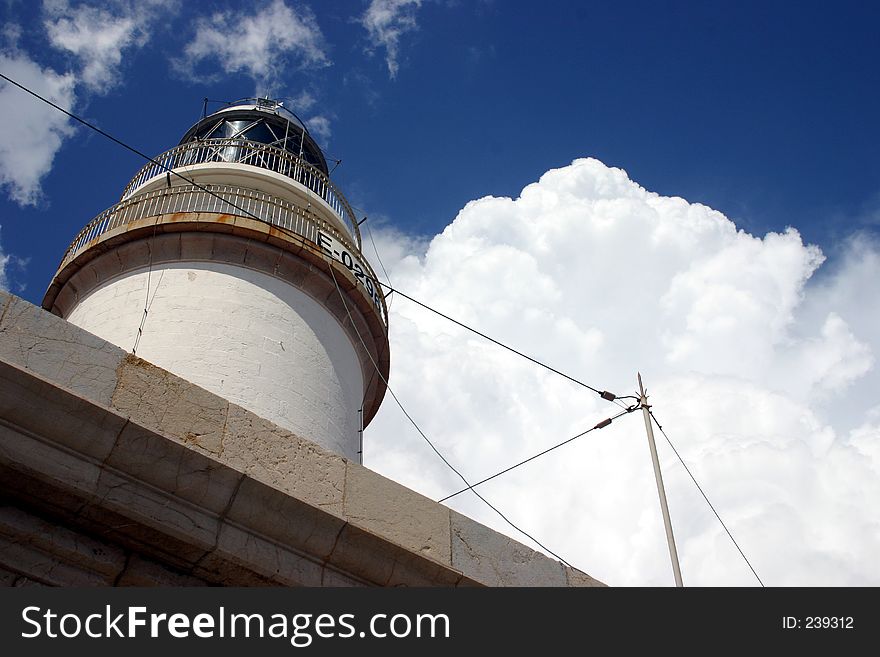 Looking up at a lighthouse with a fluffy cloud alongside