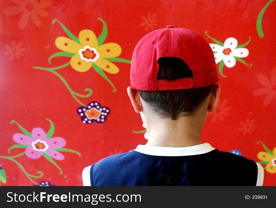 Boy with red cap on a red flowery background