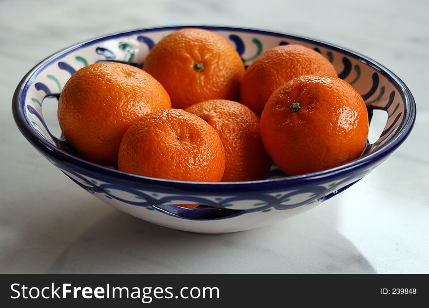 Oranges in blue,green & white dish on marble background. Oranges in blue,green & white dish on marble background