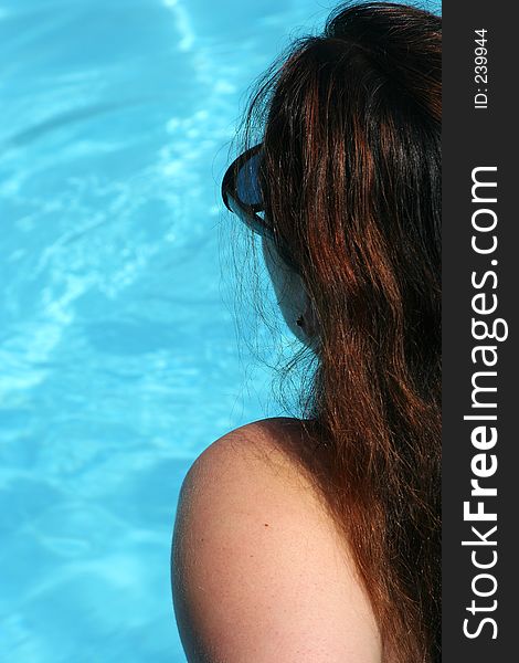 Profile of a girl with sunglasses looking to the water of a swimming pool. Profile of a girl with sunglasses looking to the water of a swimming pool