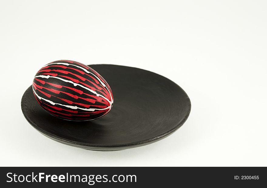 Hand colored egg on a black plate over the white background. Hand colored egg on a black plate over the white background
