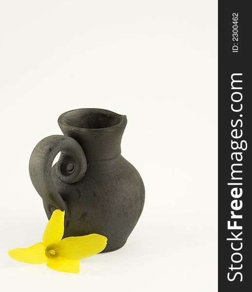 Black ceramic hand-made jar with a yellow flower - forsythia. Black ceramic hand-made jar with a yellow flower - forsythia