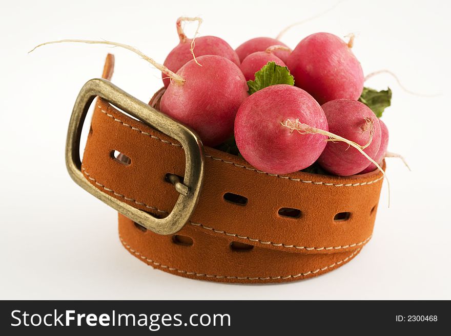 Radishes inside a belt, a concept of dieting. Radishes inside a belt, a concept of dieting