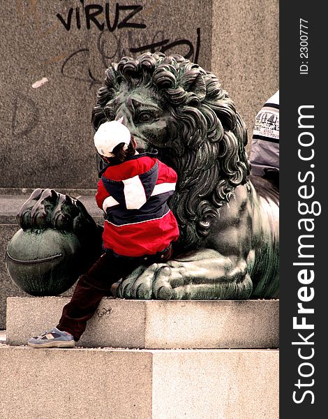 Little boy sitting on the paw of bronze lion. Little boy sitting on the paw of bronze lion