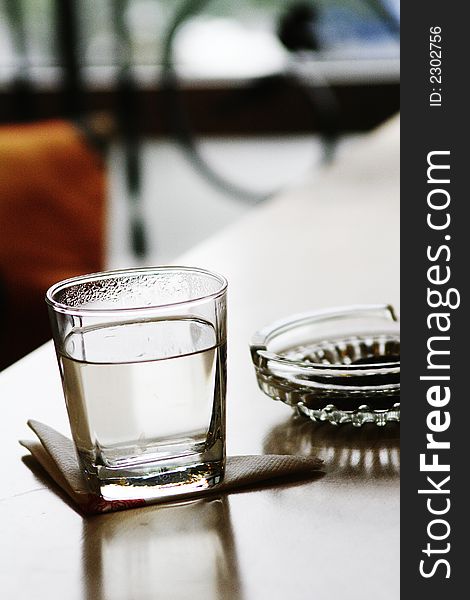 Glass and ashtray on table