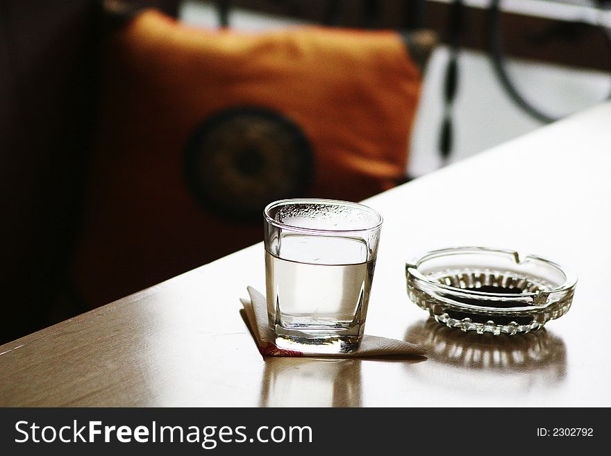 Glass and ashtray on table