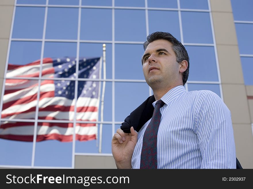 Businessman standing outside the office building with the American flag reflection in the windows. Businessman standing outside the office building with the American flag reflection in the windows