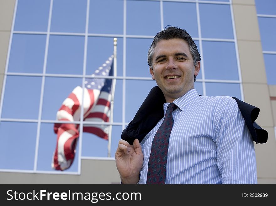 Businessman standing outside the office building with the American flag reflection in the windows. Businessman standing outside the office building with the American flag reflection in the windows