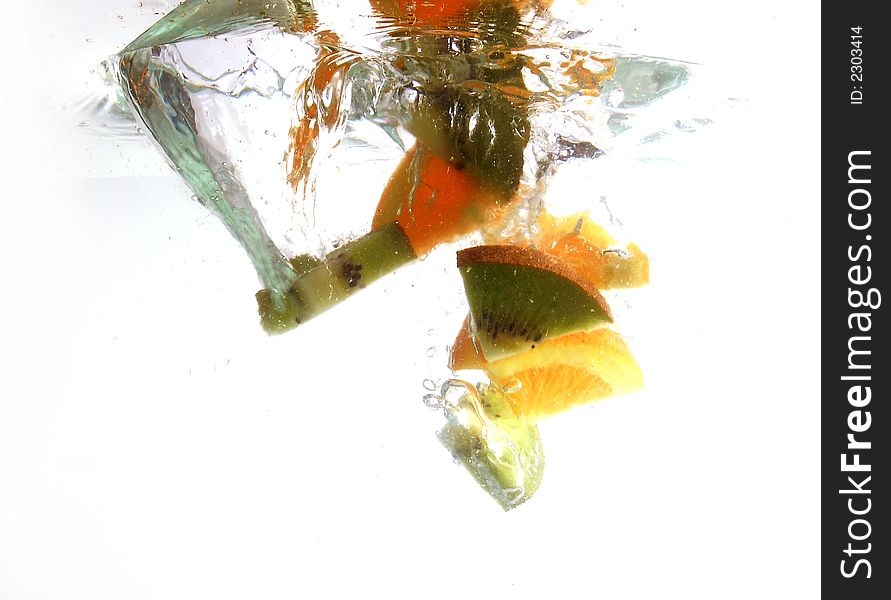 Kiwi and orange slices splashing in water. Kiwi and orange slices splashing in water